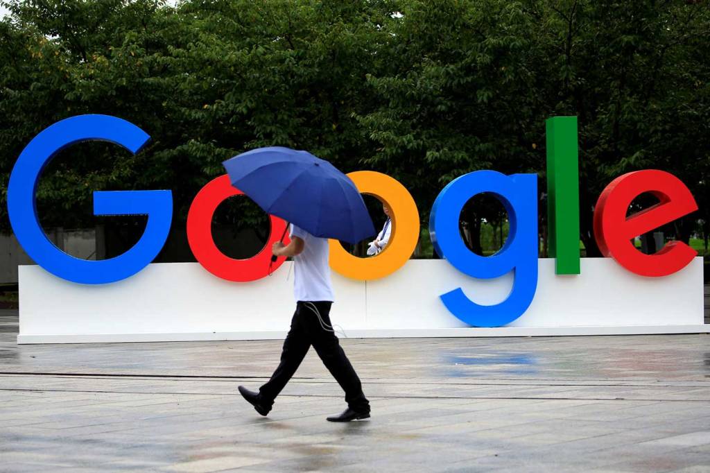 Pessoa caminhando em frente ao logo do Google