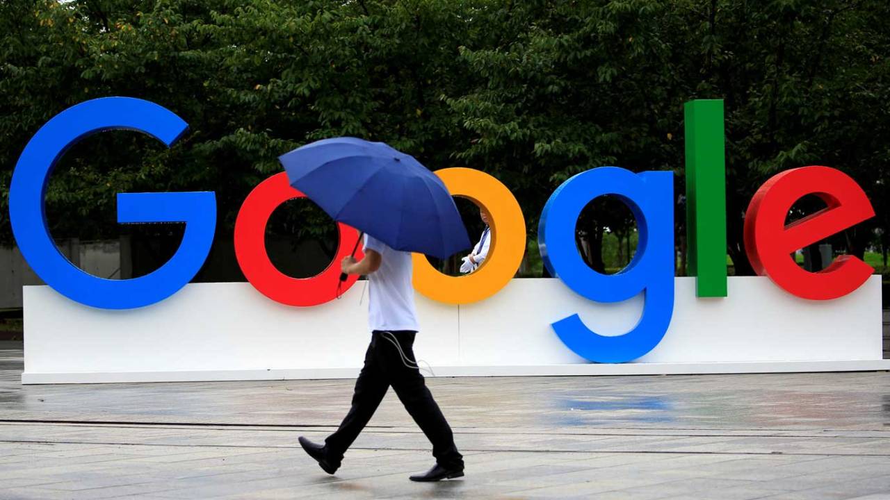 Pessoa caminhando em frente ao logo do Google