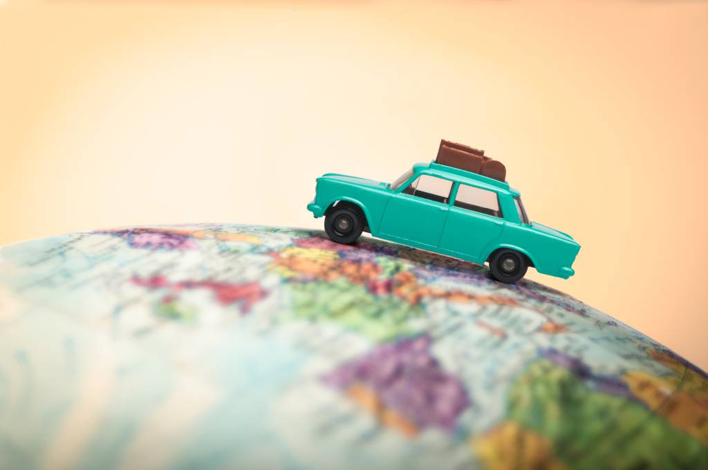 Imagem mostra um carrinho de brinquedo, verde, andando sobre o globo terrestre