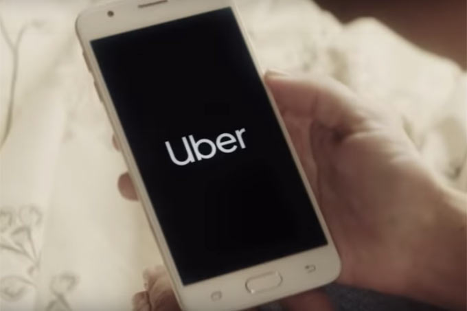 Uma mão segura um smartphone que está com o aplicativo da Uber aberto