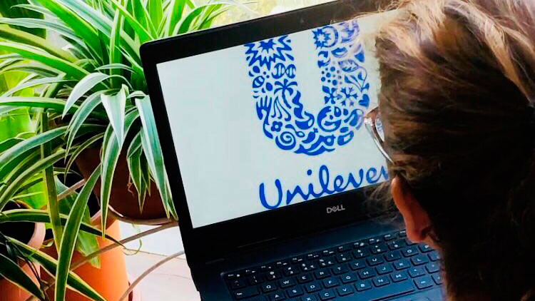 Imagem mostra uma pessoa utilizando um computador. Na tela do aparelho, está o logo da Unilever