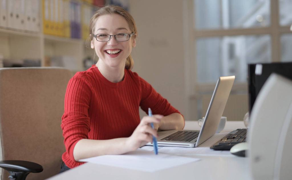 Mulher jovem sorrindo e usando o computador