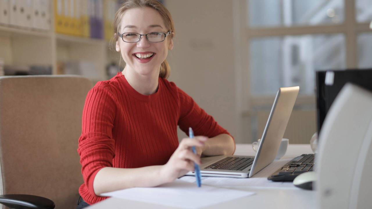 Mulher jovem sorrindo e usando o computador