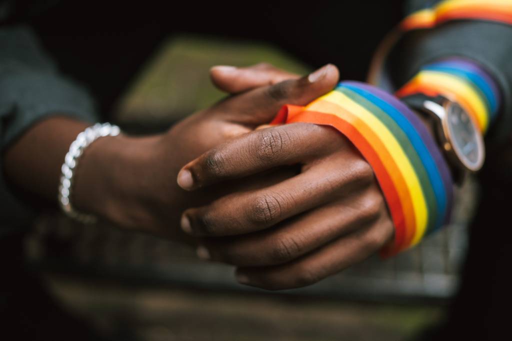 Mãos negras segurando uma faixa LGBT+