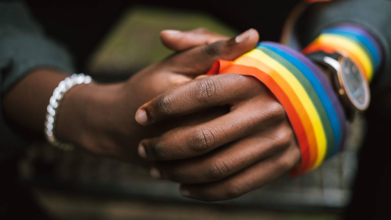 Mãos negras segurando uma faixa LGBT+