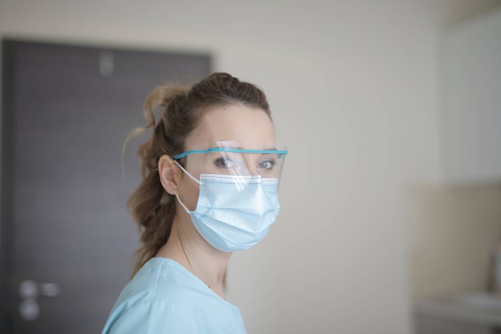 Mulher da área de saúde com máscara e óculos de proteção