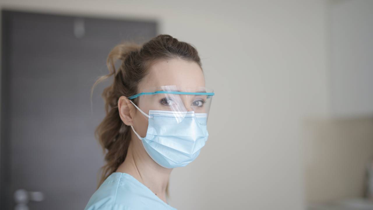 Mulher da área de saúde com máscara e óculos de proteção