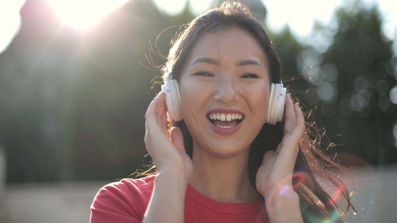 Mulher oriental sorrindo com fones de ouvido