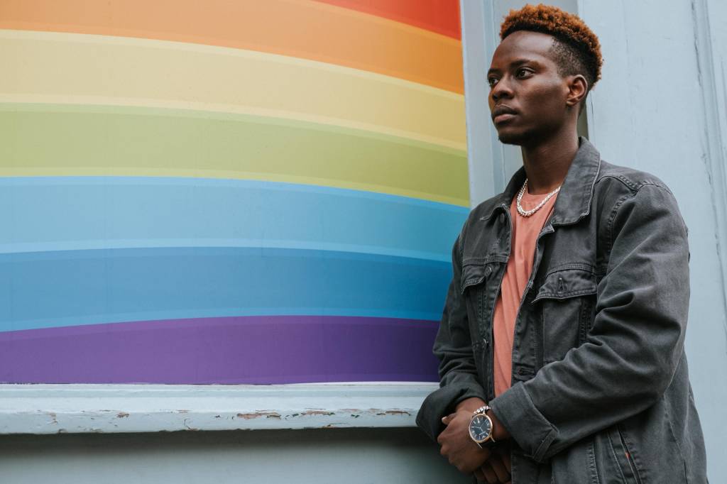 Jovem negro ao lado de uma bandeira LGBT+