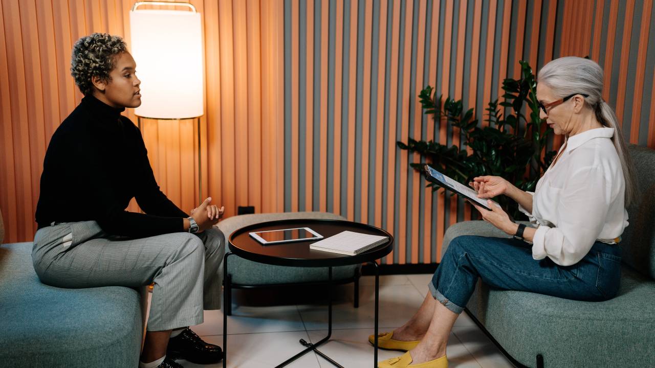 Mulher negra e mulher com cabelos grisalhos conversando numa entrevista de emprego