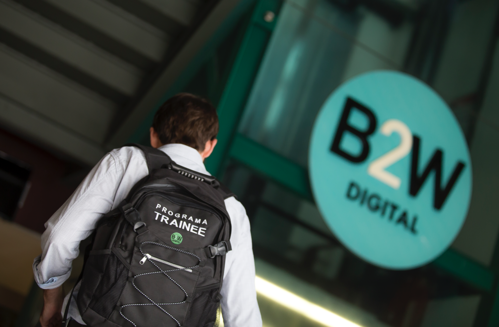 Imagem mostra um homem de costas com a mochila com a marca da B2W entrando no prédio da B2W.