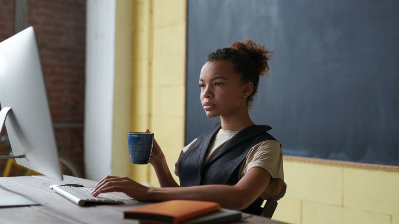 Uma mulher negra aparece trabalhando usando o computador.
