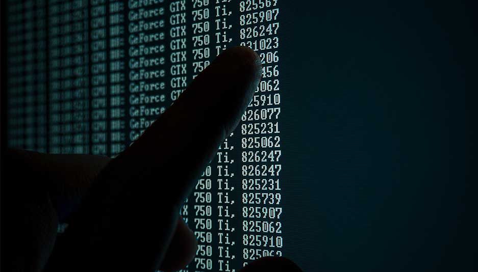 Mão apontando uma tela de computador com dados numéricos;