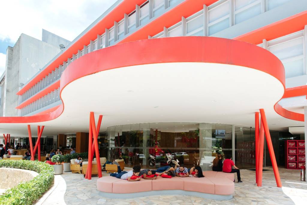 Imagem mostra a sede do iFood, um prédio baixo e curvado, pintado de branco e vermelho