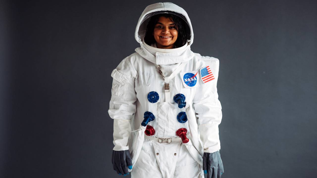 Uma mulher aparece usando um traje de astronauta com um logo da Nasa.