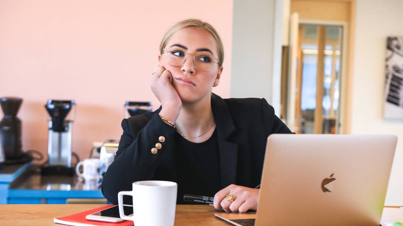 Imagem mostra mulher loira, usando computador, com expressa entediada