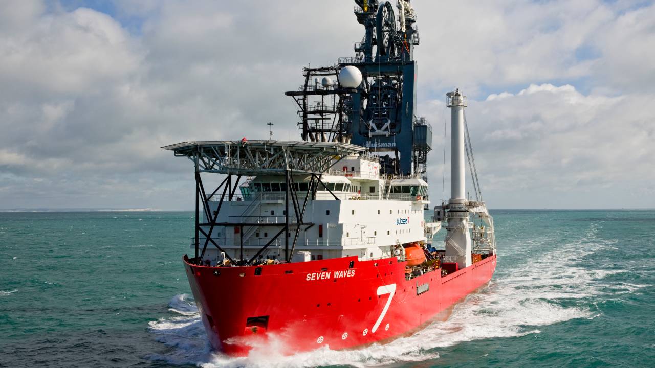 Imagem mostra um barco grande, vermelho e branco, no meio do mar