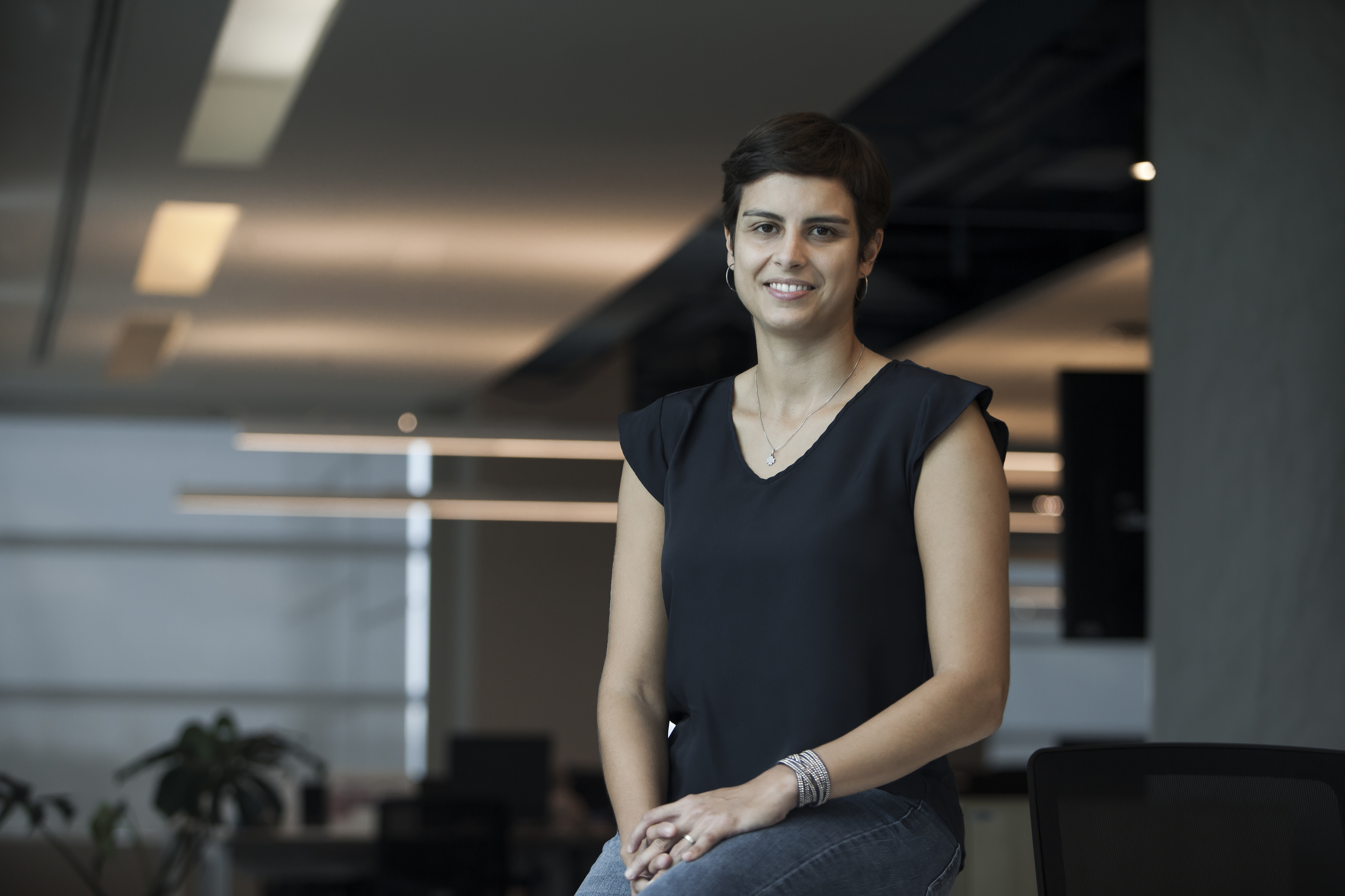 Imagem mostra Flavia Caroni, uma mulher branca, de cabelos escuros e curtos, que está sorrindo para a foto