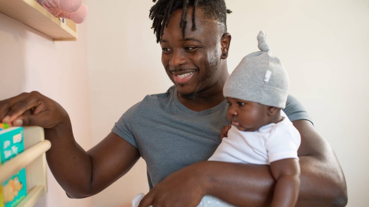Homem negro com um bebê no colo.