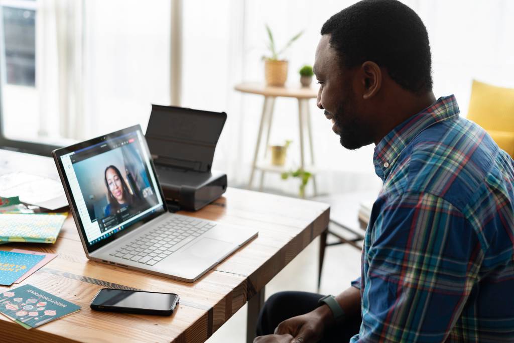 Imagem mostra um homem negro numa videconferência conversando com uma mulher negra