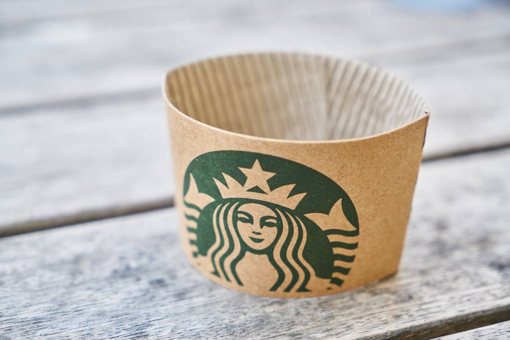 Imagem mostra um porta-copos de papelão do Starbucks sobre uma superfície de madeira