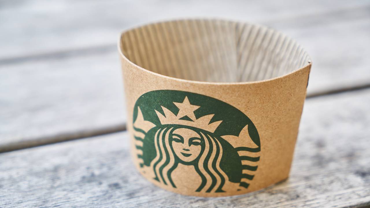 Imagem mostra um porta-copos de papelão do Starbucks sobre uma superfície de madeira
