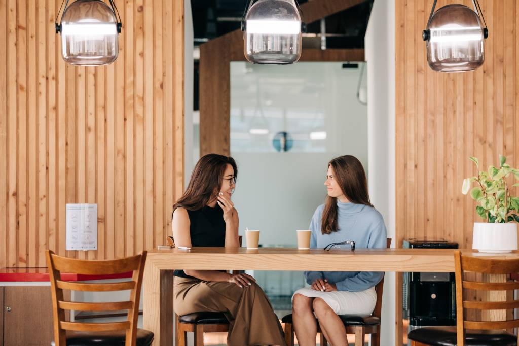 Duas mulheres conversam em um ambiente descontraído do escritório