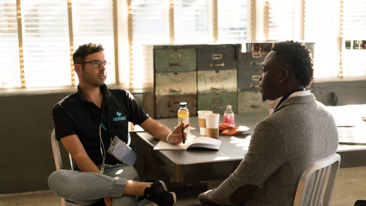 Dois homens estão sentados a uma mesa enquanto conversam