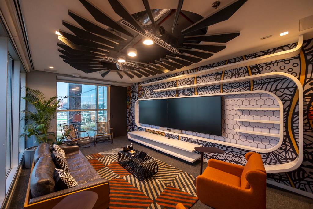 Disney Pantera Negra Sala de reunião com sofás, televisão e mesa central. O ambiente é todo decorado com o tema de Pantera Negra