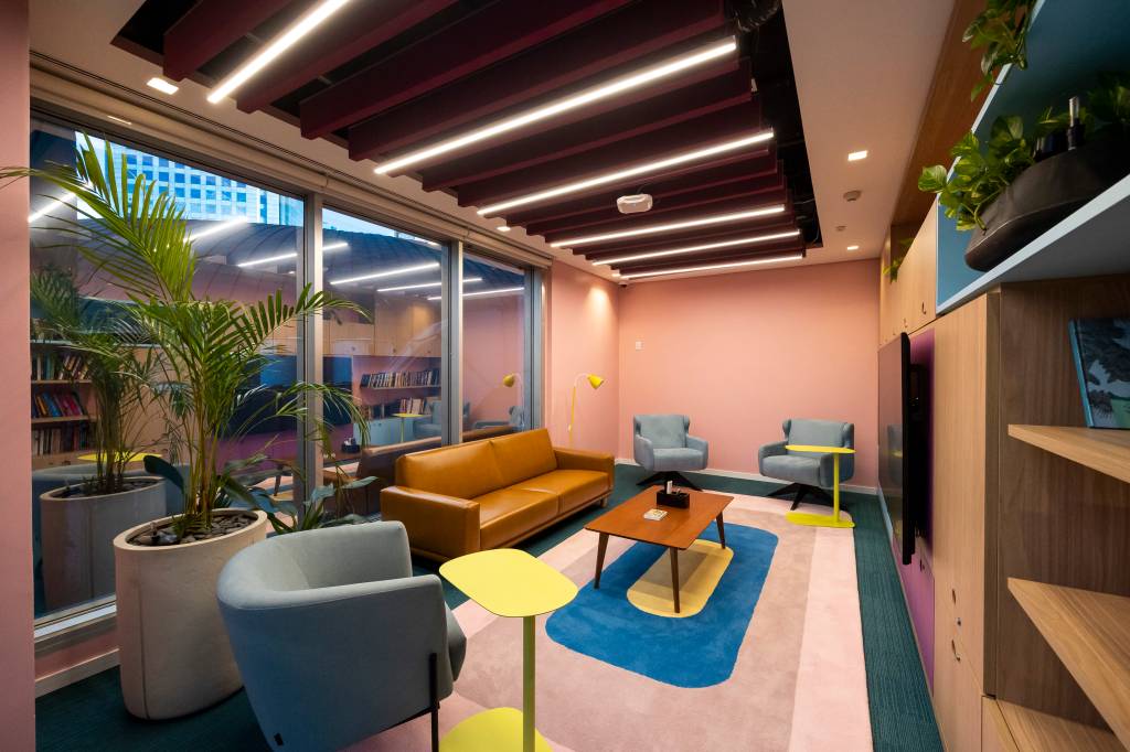 Disney Simpsons Sala com um sofá, algumas poltronas e uma mesa de centro. O chão é coberto por um carpete nas cores azul e rosa