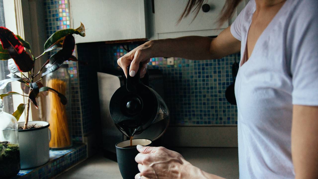Uma mulher está enchendo uma xícara de café