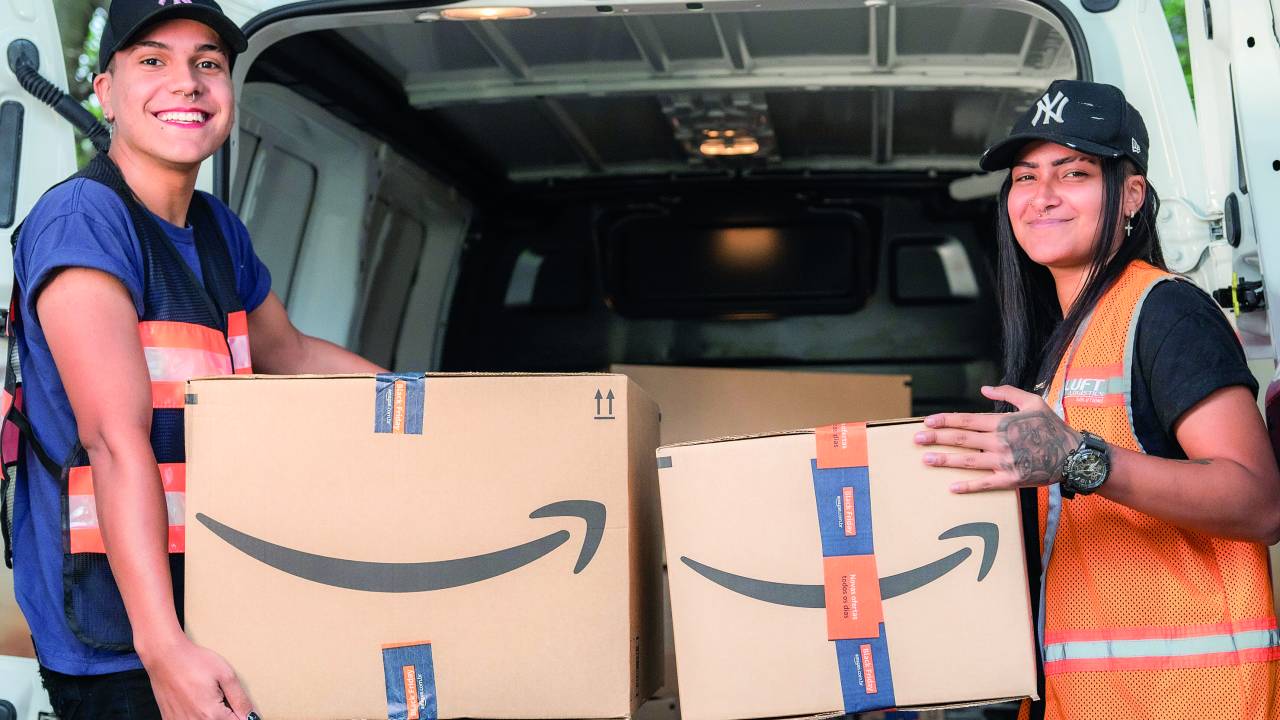 Duas pessoas seguram caixas de papelão da Amazon
