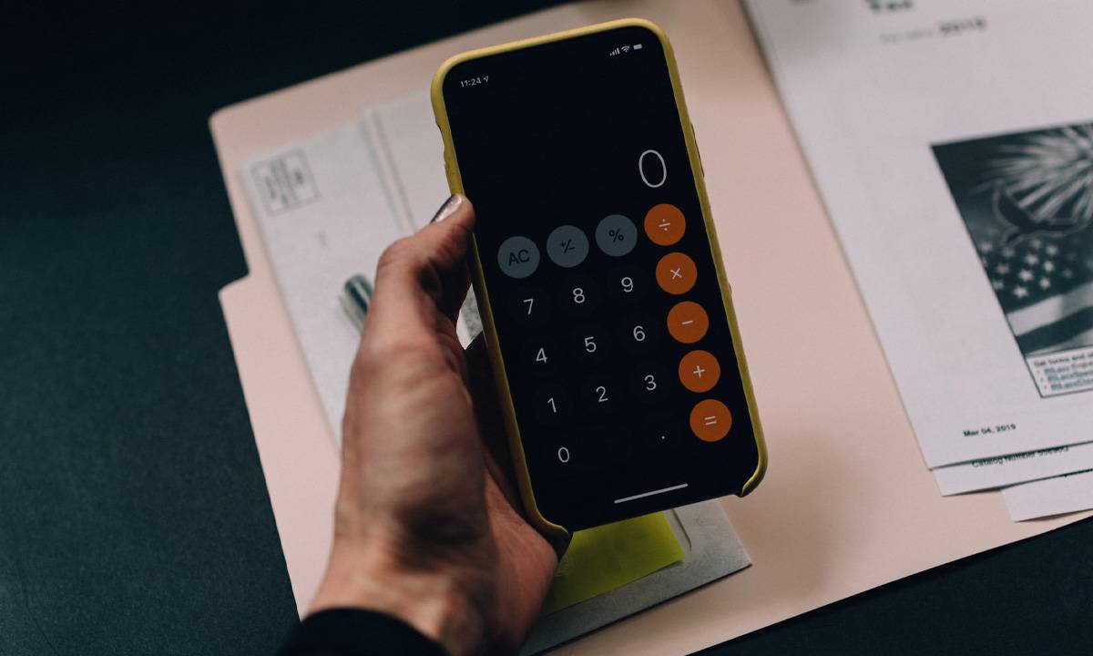 imagem de uma pessoa segurando o celular com a calculadora aberta