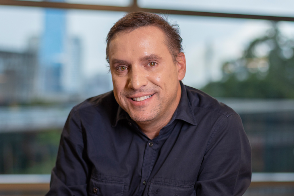 VCRH_95_IA_no_RH_3 Foto de um homem sorrindo usando camisa azul escura.