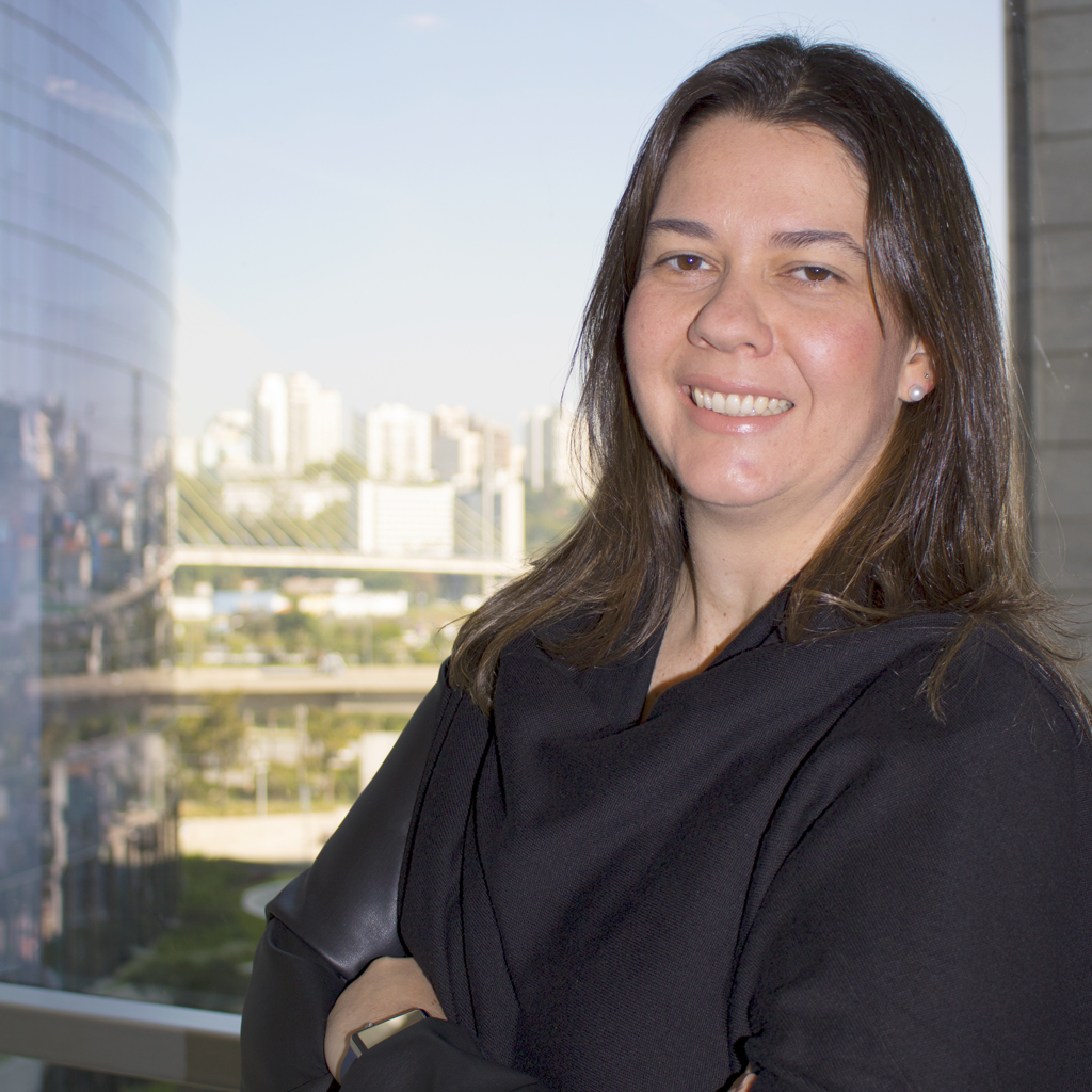 Imagem de executiva sorrindo, vestindo uma roupa preta.