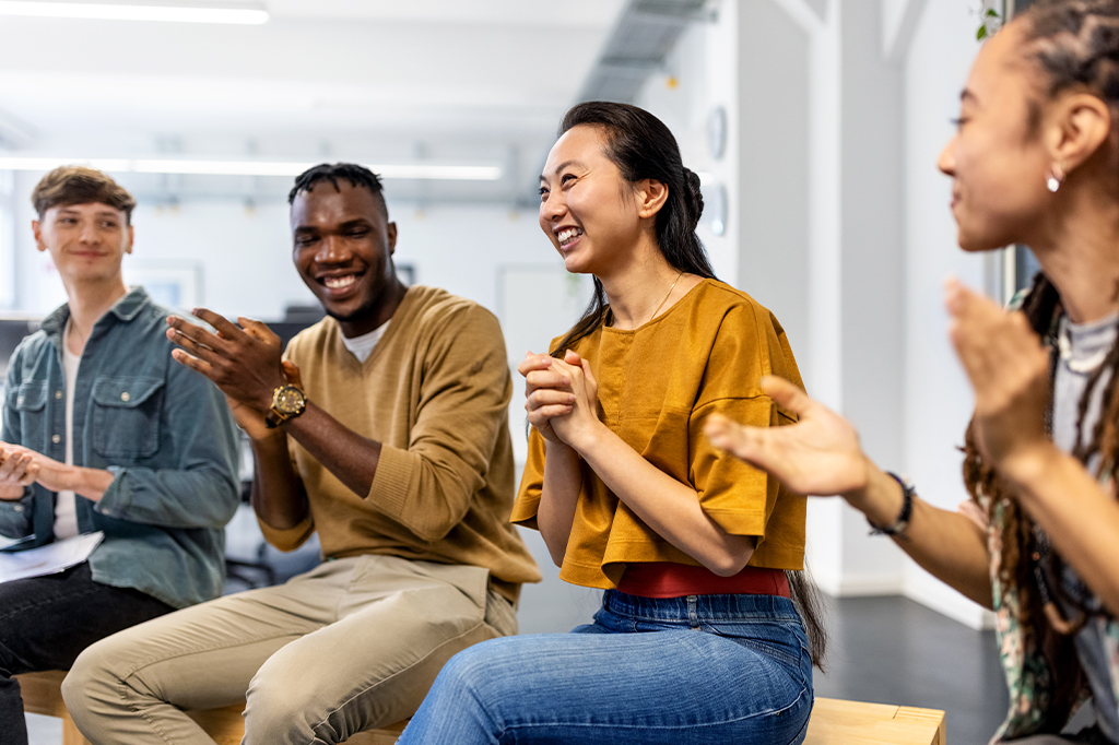 Fotografia de um grupo de pessoas sorrindo em um reunião de trabalho.