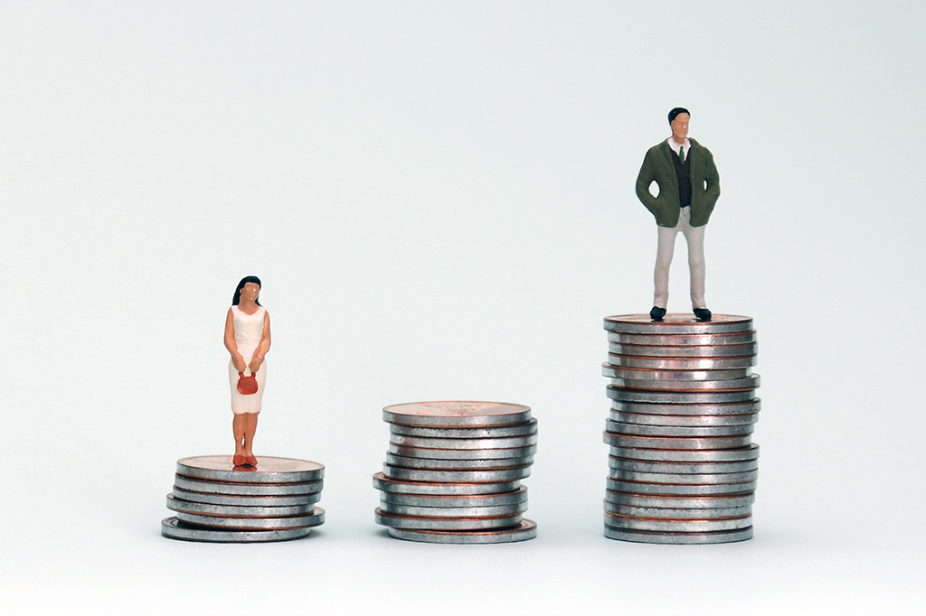 Fotografia de uma mulher em miniatura em uma pilha de moedas de baixas e um homem em miniatura em uma pilha de moedas de altas.