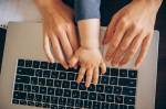 Fotografia de uma mãe e seu bebê com as mãos em um laptop trabalhando.