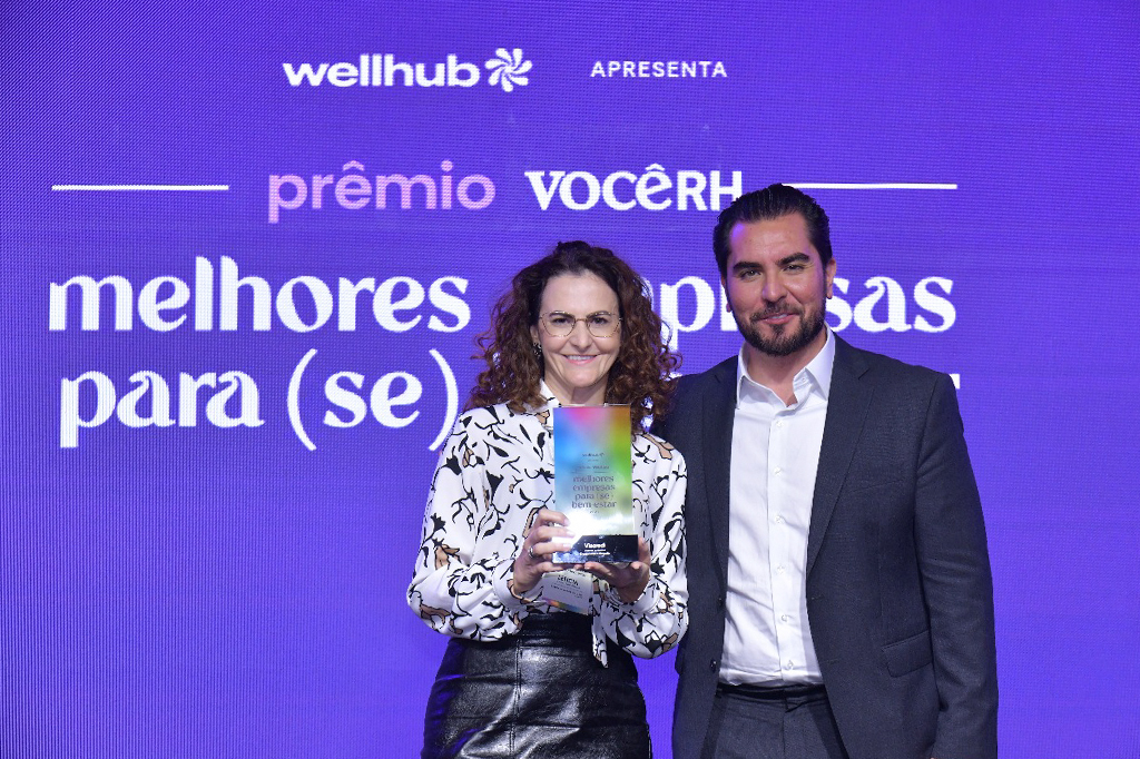 Um homem e uma mulher lado a lado segurando um troféu com as mãos.