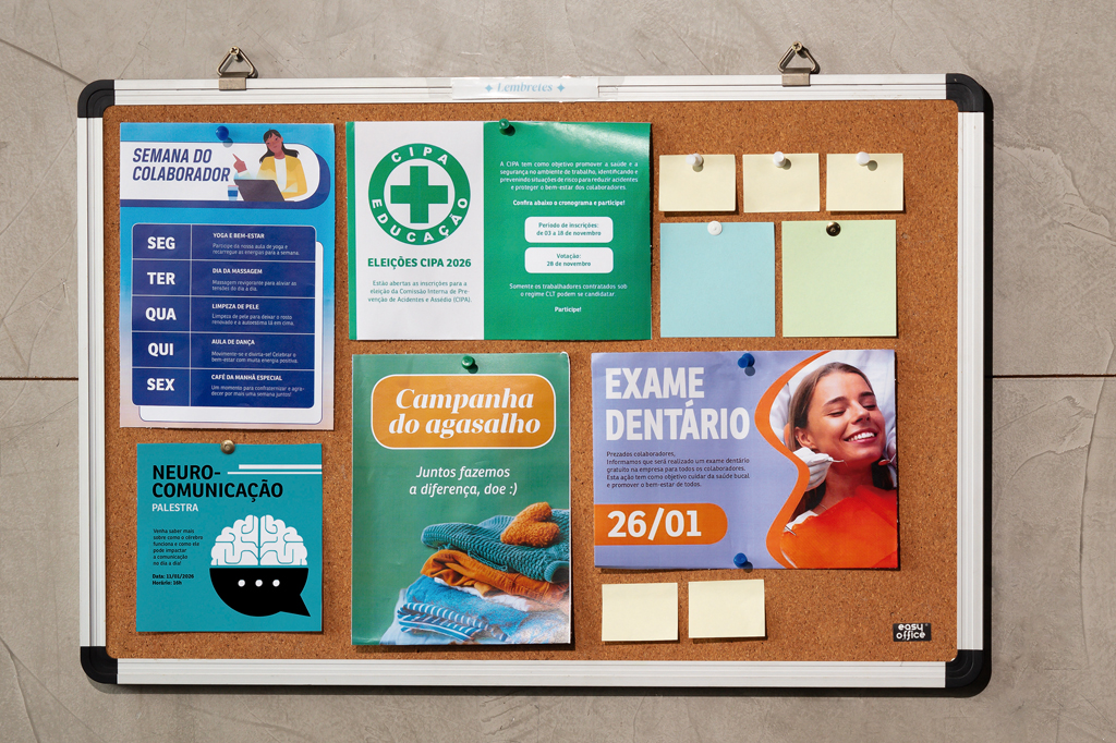 Imagem de uma parede, revestida de azulejos, com um painel feito de cortiça e diversos cartazes sobre ele.