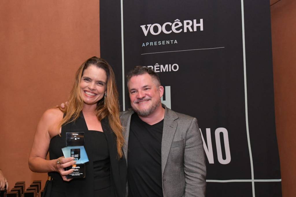 Mulher recebendo troféu ao lado de editor-chefe da Você RH.